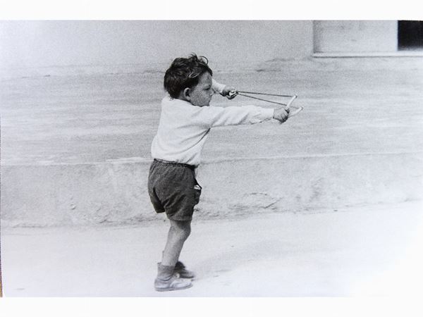 Mario Dondero : Bambino con fionda 1977  ((1928-2015))  - Auction A Trip into Photography: Ghirri, Berengo-Gardin, Giacomelli, Vasiliev, Salgado… - Maison Bibelot - Casa d'Aste Firenze - Milano