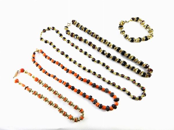 Four necklaces and a bracelet in different gold alloys and metal with garnets, corals and glasses