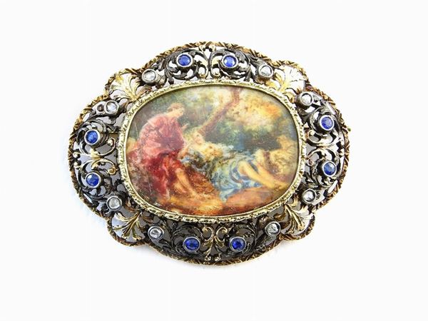 Yellow gold and silver brooch with miniature in the middle set with diamonds and sapphires