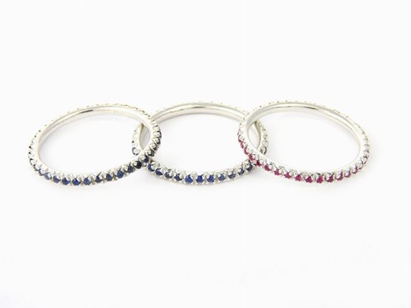 Three white gold eternity rings with sapphires (two items) and rubies (one item)
