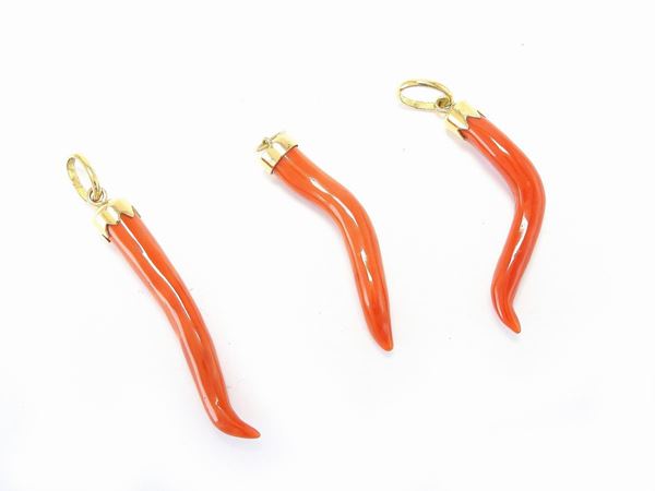 Three yellow gold and red coral good luck amulets