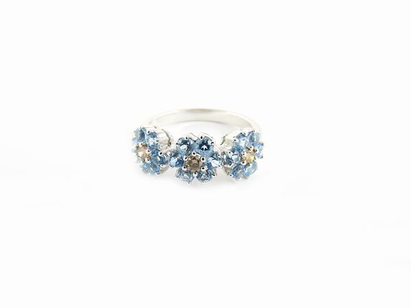 White gold ring with brown diamonds and light blue topazes