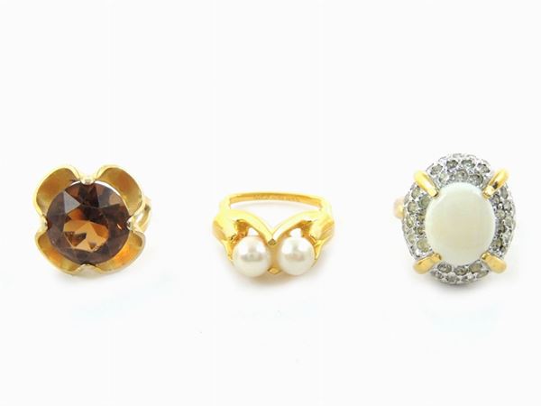 Tre anelli in metallo dorato, strass, vetro e perle simulate