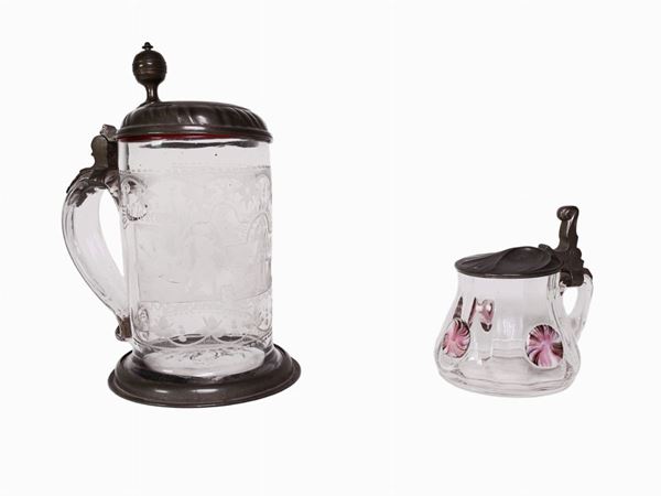 A glass tankard with a pewter lid and a small glass and a pewter lid