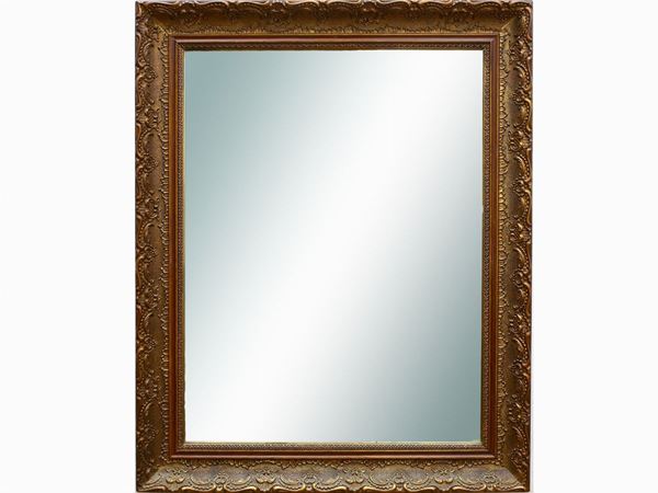 A wall mirror with golden pastiglia frame