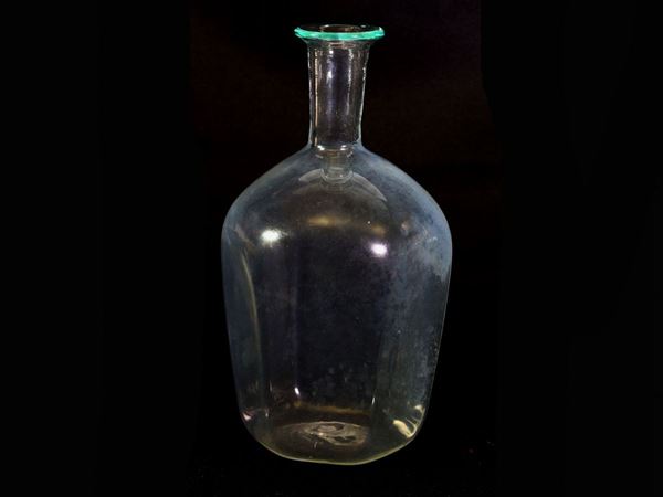 A trasparent glass bottle with green rim