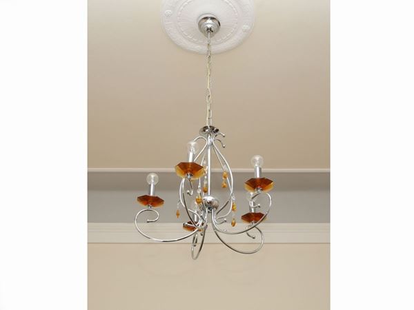 A chromed chandelier with a pair of table lamps