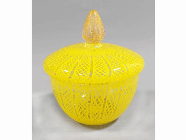 A glass blown box with a yellow reticello filigree decor