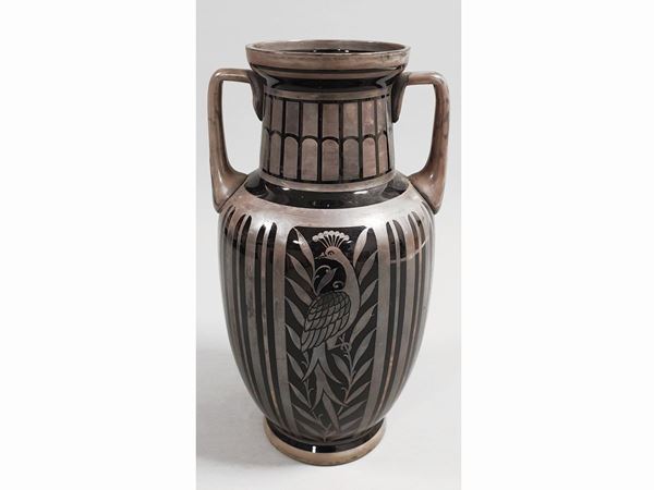 A two-handled black glass vase with silver decor of peacocks and foliage.