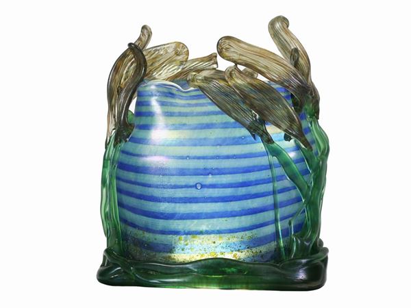 A blue and green striped glass vase with wavy mouth and hot application of leaves.