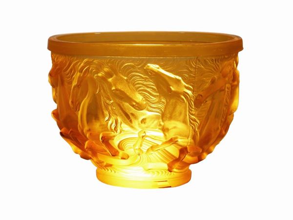 A glass vase pressed in an ocher-colored mold with a subject of horses in relief