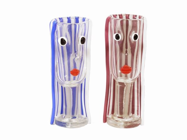 A pair of glass with stylized faces the hair made of milk glass, one pink  one blue