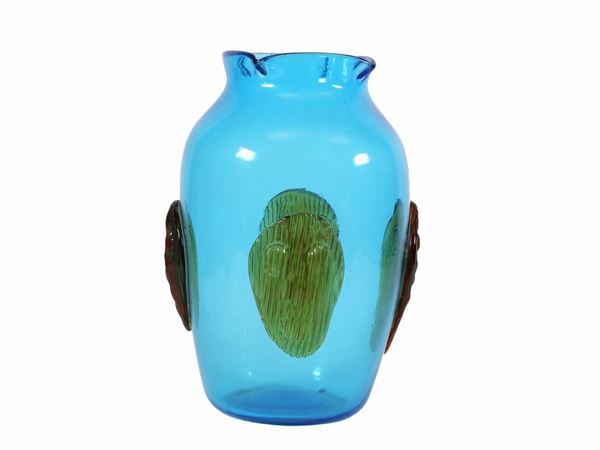A blue glass vase worked with pliers and applications of stylized faces.