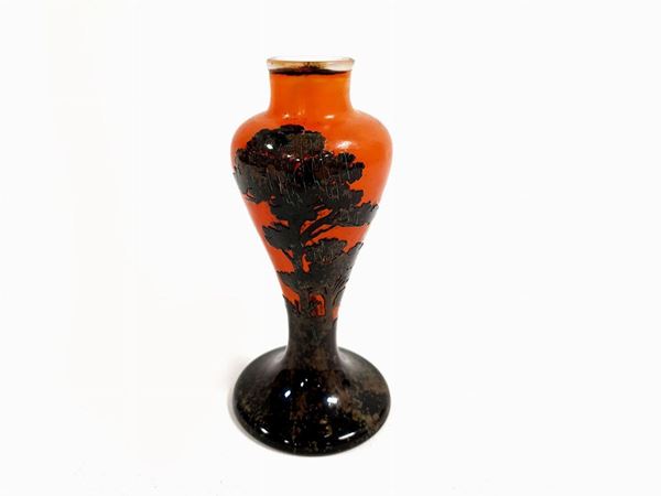 A small Gallé glass vase decorated with dark trees on an orange background. Signed
