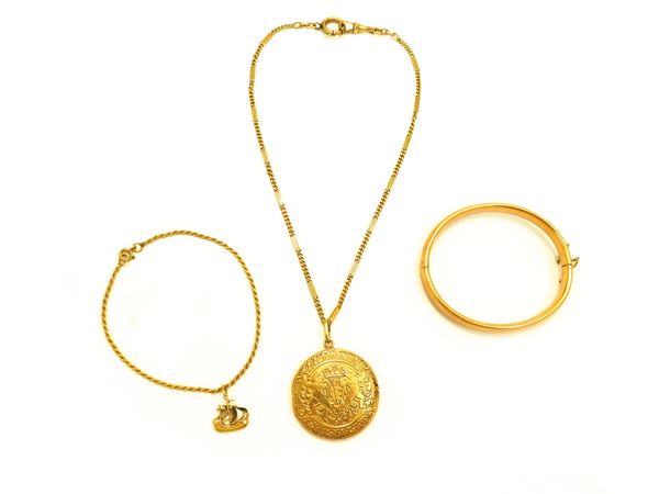Due bracciali e una catena da orologio con pendente portaritratto in oro giallo