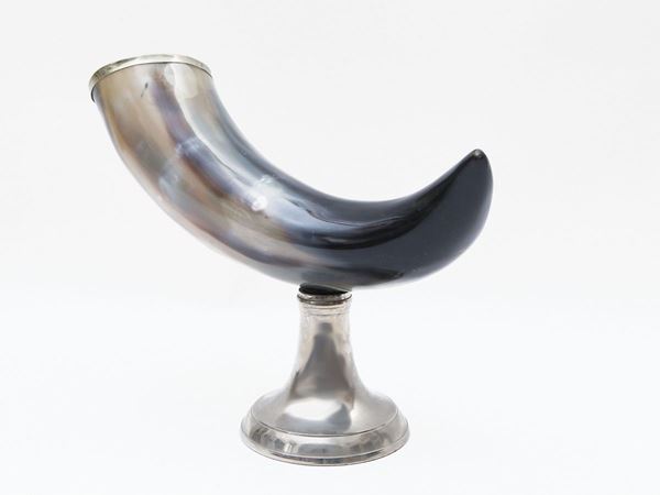 Cattle horn on a circular base in silver metal