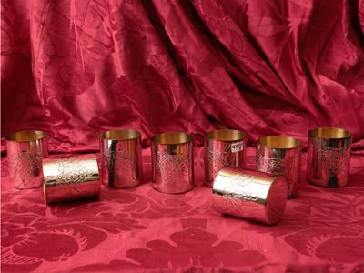 Serie di otto bicchieri da vino in argento, sbalzati con grappoli d'uva e interno vermeil