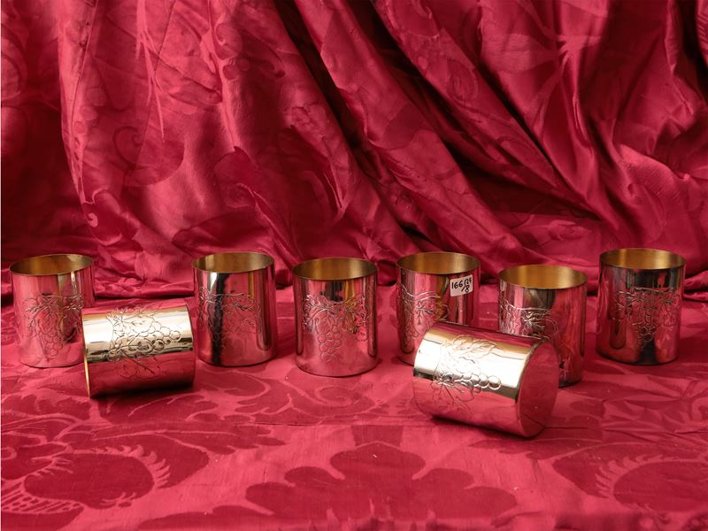 Serie di otto bicchieri da vino in argento, sbalzati con grappoli d'uva e interno vermeil