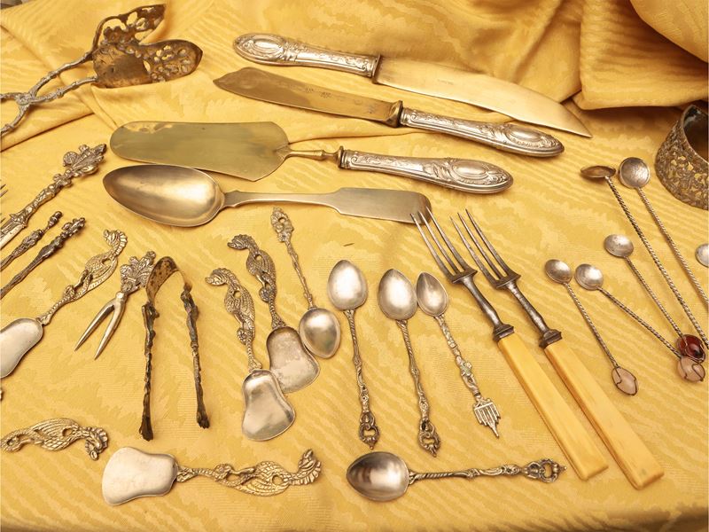 Grande assortimento di posate in metallo argentato e dorato con accessori da tavola