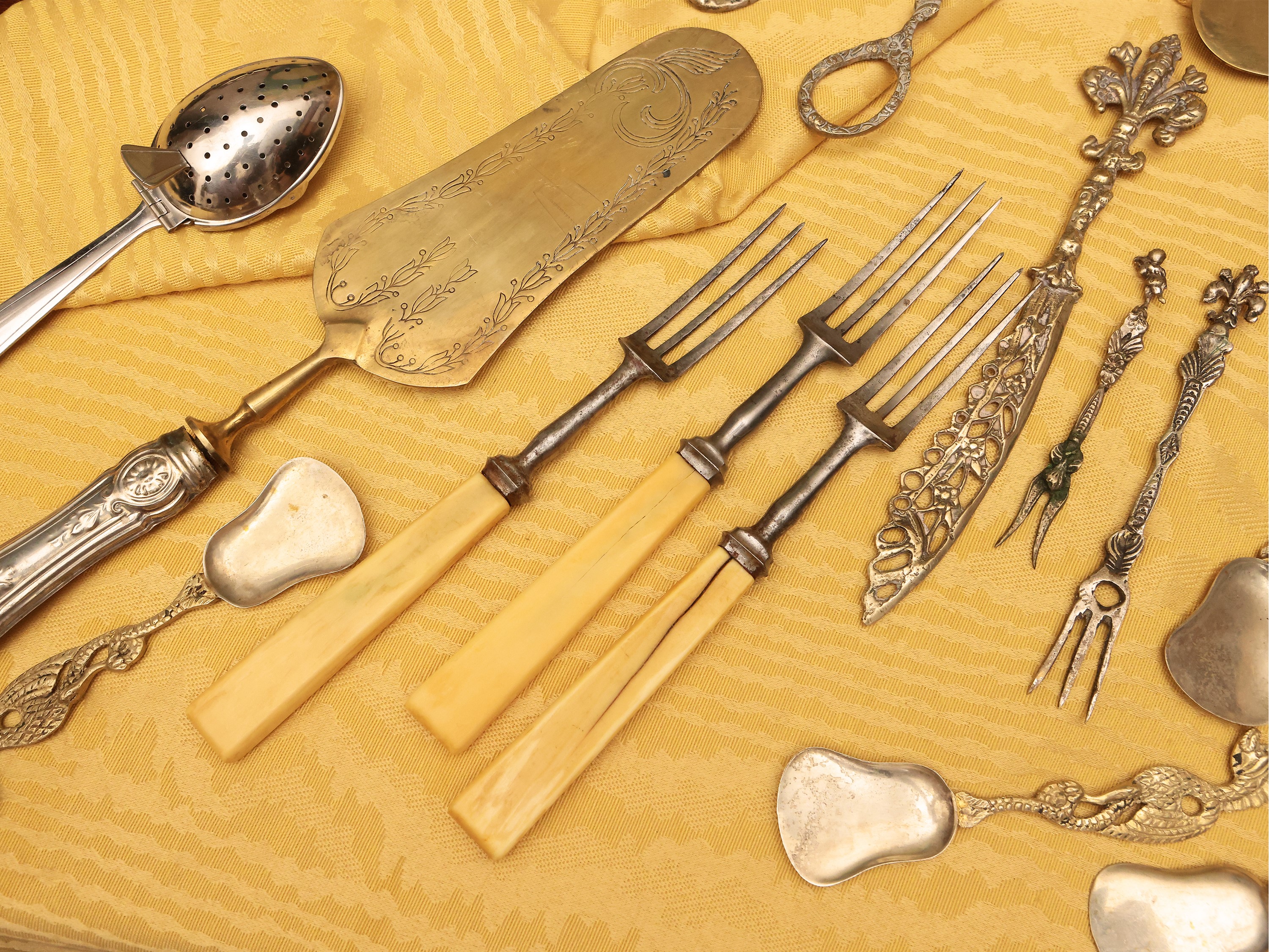 Grande assortimento di posate in metallo argentato e dorato con accessori da tavola