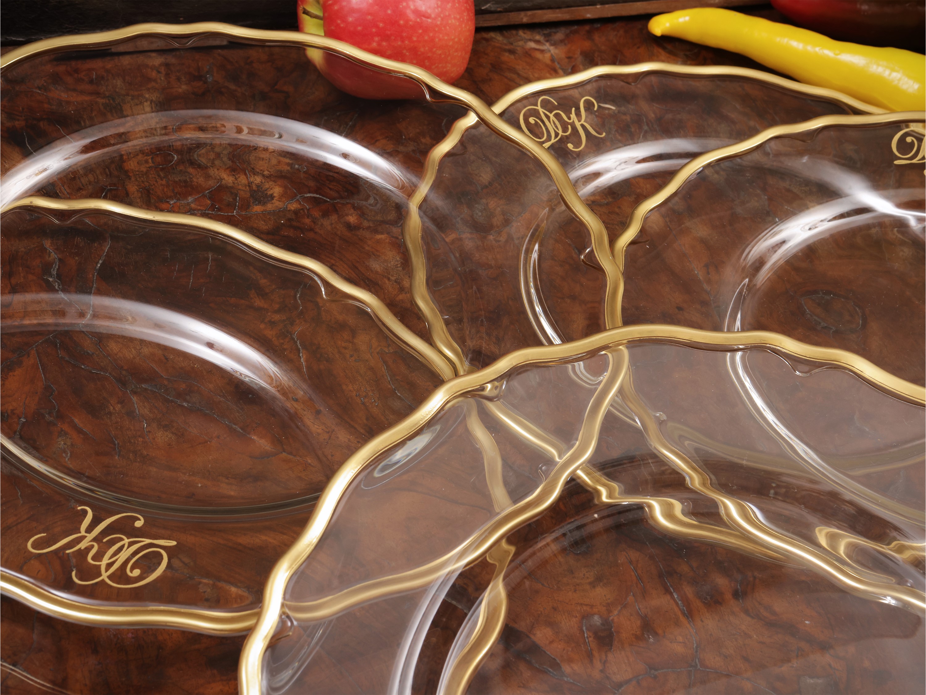 Serie di dodici sottopiatti in vetro trasparente con bordo mosso e decorazione in oro
