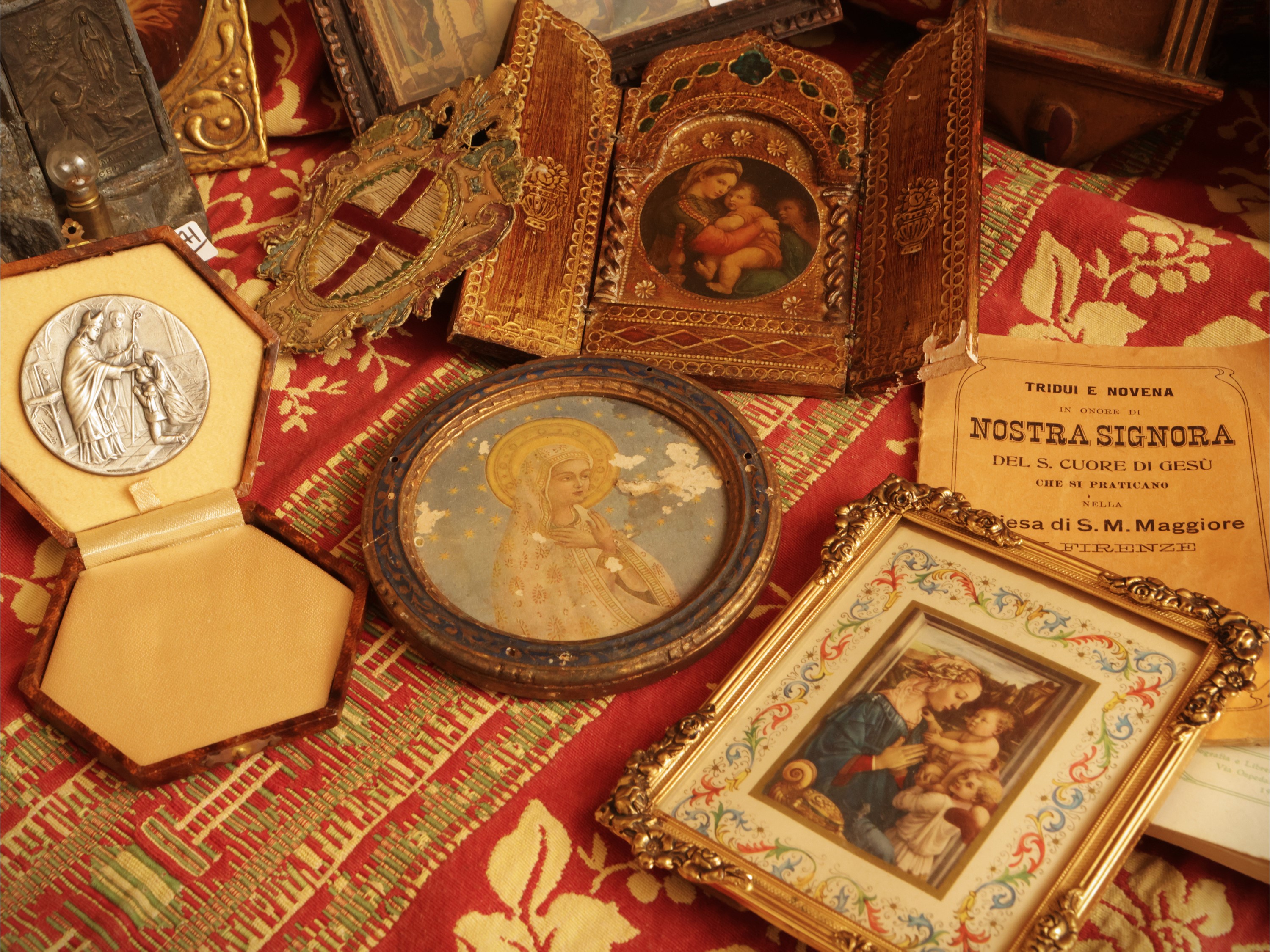 Miscellanea di curiosità devozionali: assemblaggio di spille, monete, pendenti, icone e dipinti