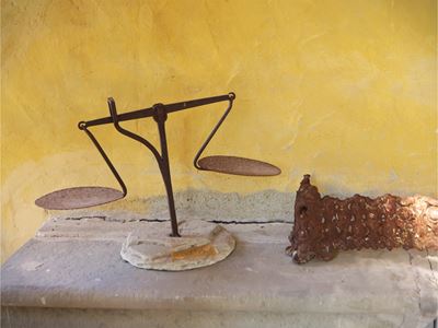 Due accessori in ferro battuto: bilancia con base in pietra e ringhiera traforata