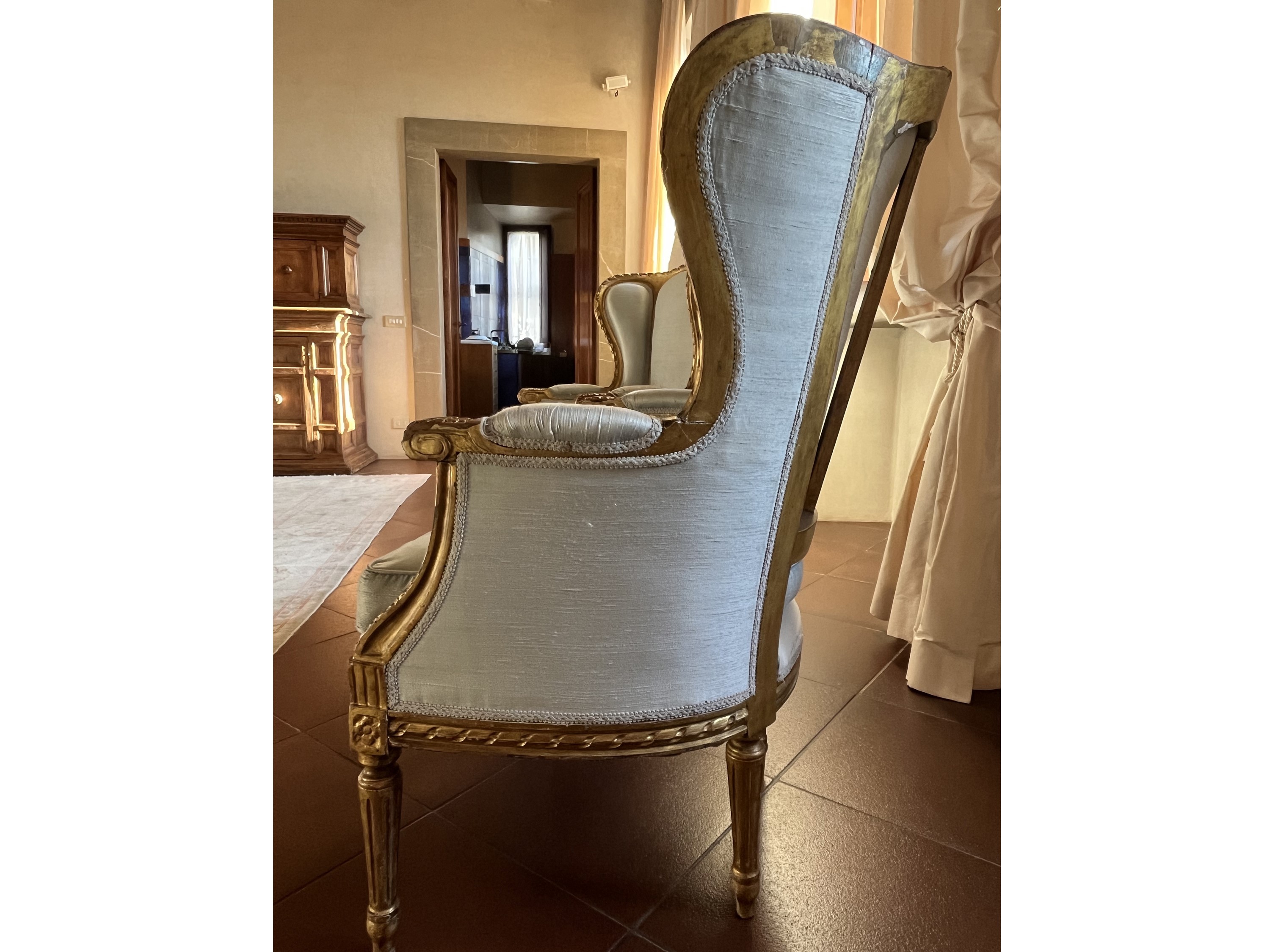 Poltrona bergère imbottita, velluto celeste polvere con bordura frangiata