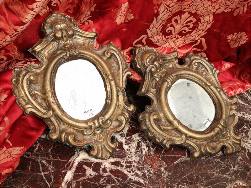 Coppia di piccole specchiere con cornice in tole dorata, motivi a volute