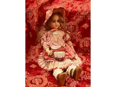 Bambola in biscuit, occhi in vetro e abito in raso color rosa antico (inizio XX secolo)