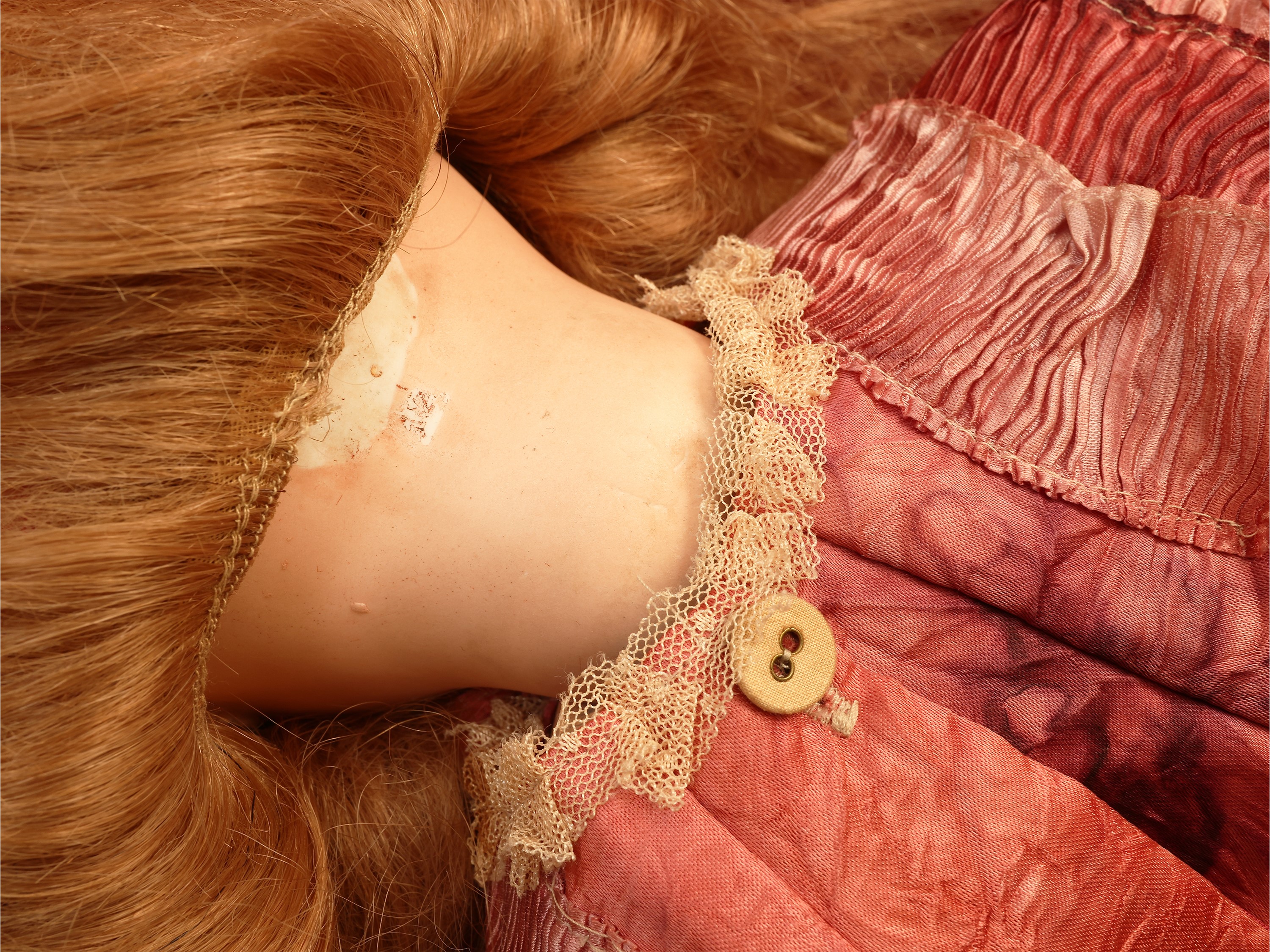Bambola in biscuit, occhi in vetro e capelli biondi, abito in raso (inizio XX secolo)