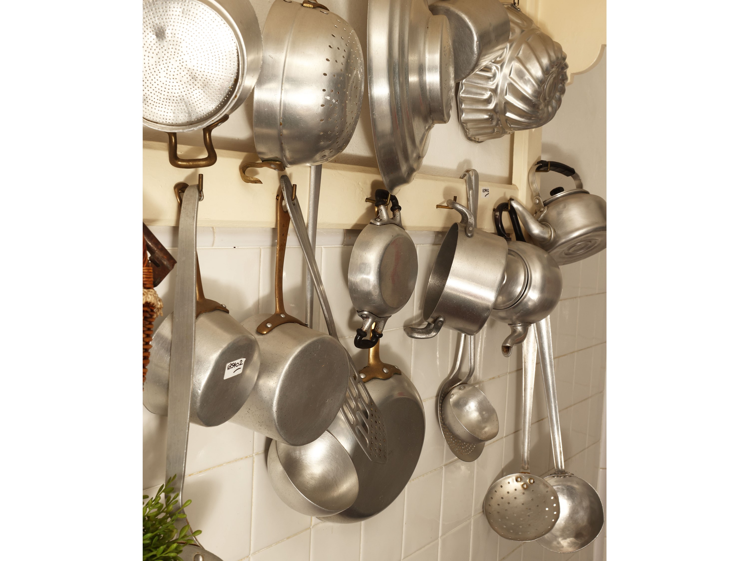 Piattaia rustica in legno tinto bianco con assortimento di tegami ed accessori in alluminio