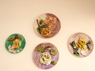 Quattro piatti da parata in ceramica policroma, decorati con motivi floreali in rilievo