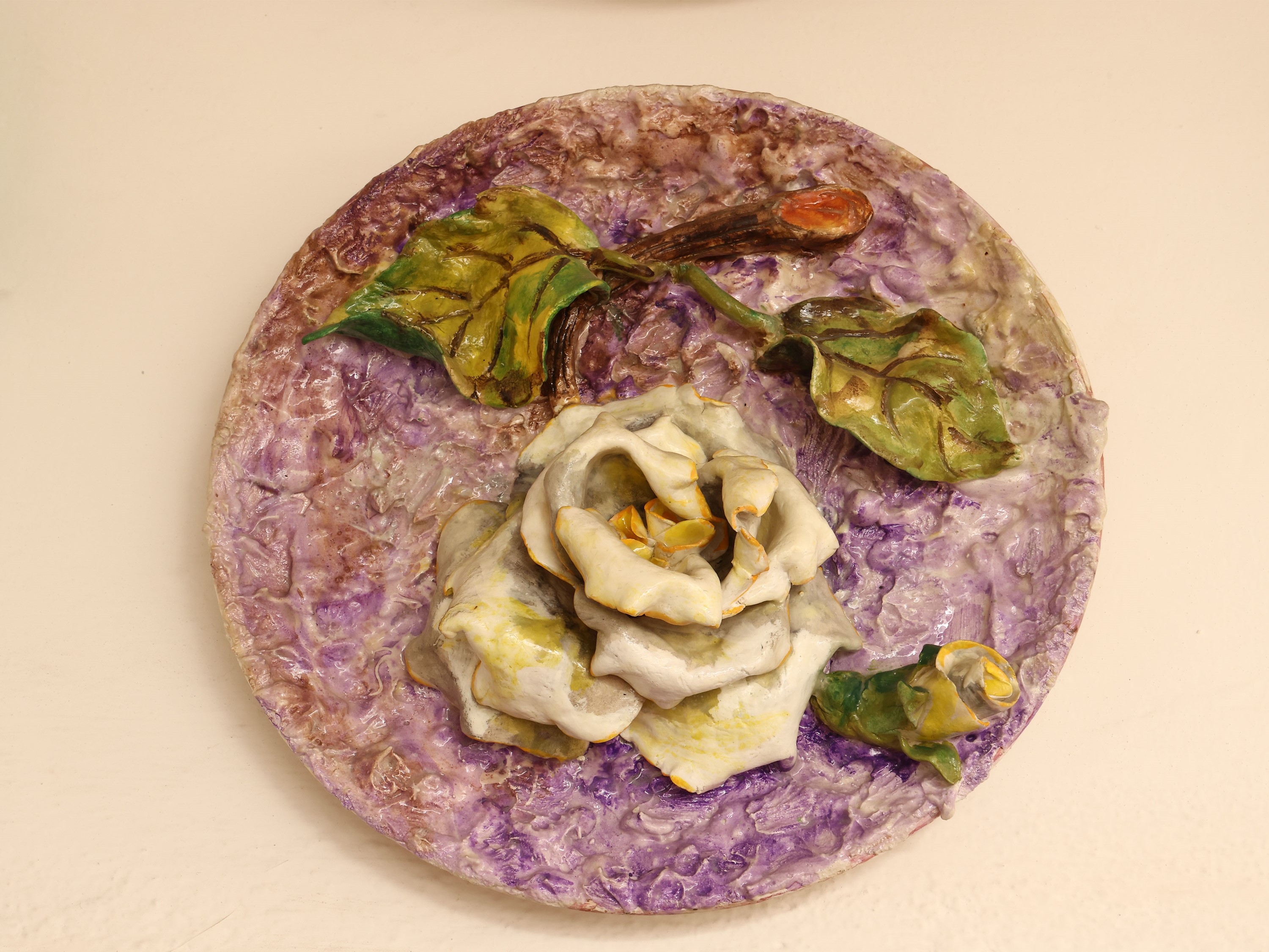 Quattro piatti da parata in ceramica policroma, decorati con motivi floreali in rilievo