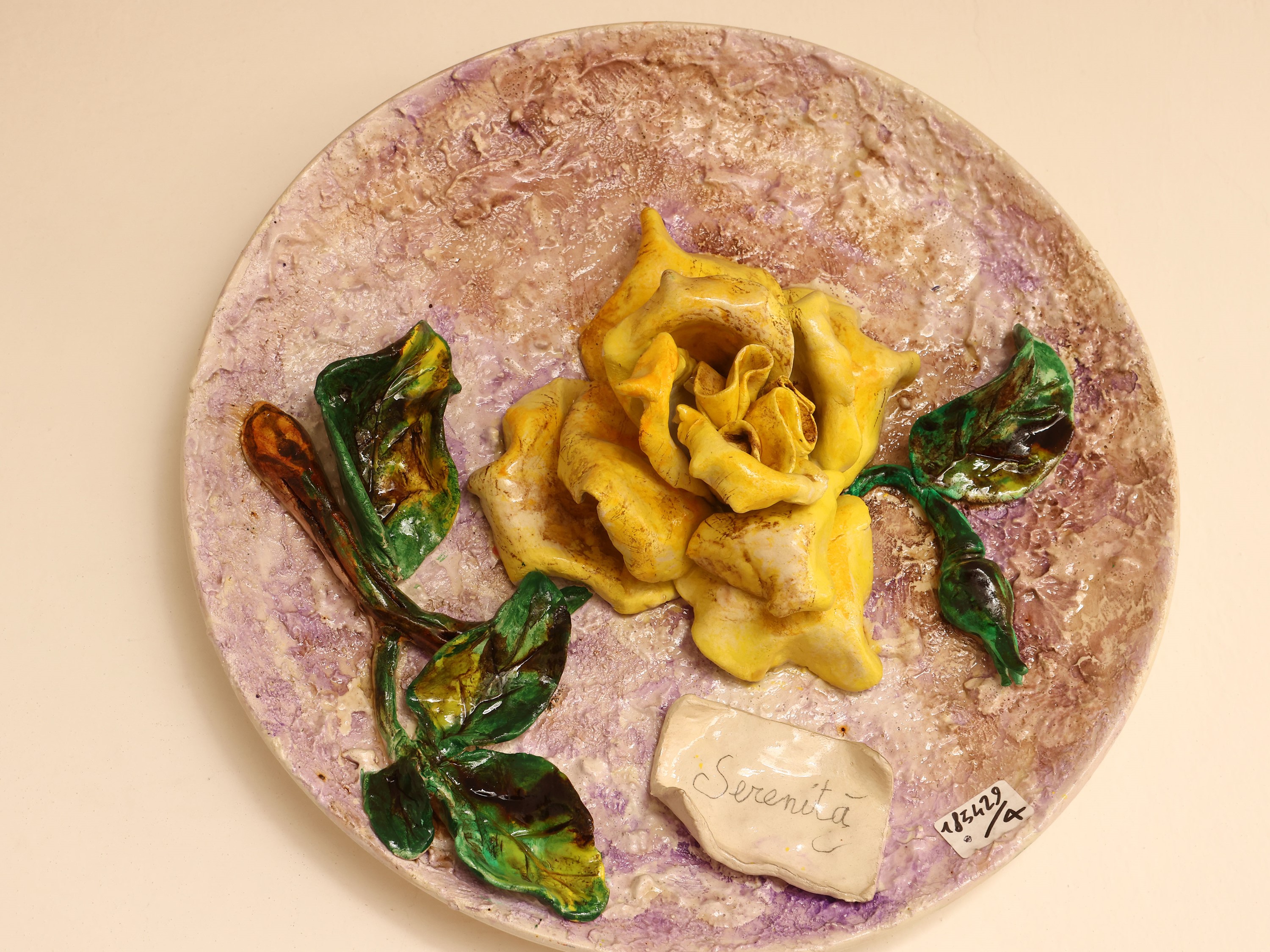 Quattro piatti da parata in ceramica policroma, decorati con motivi floreali in rilievo