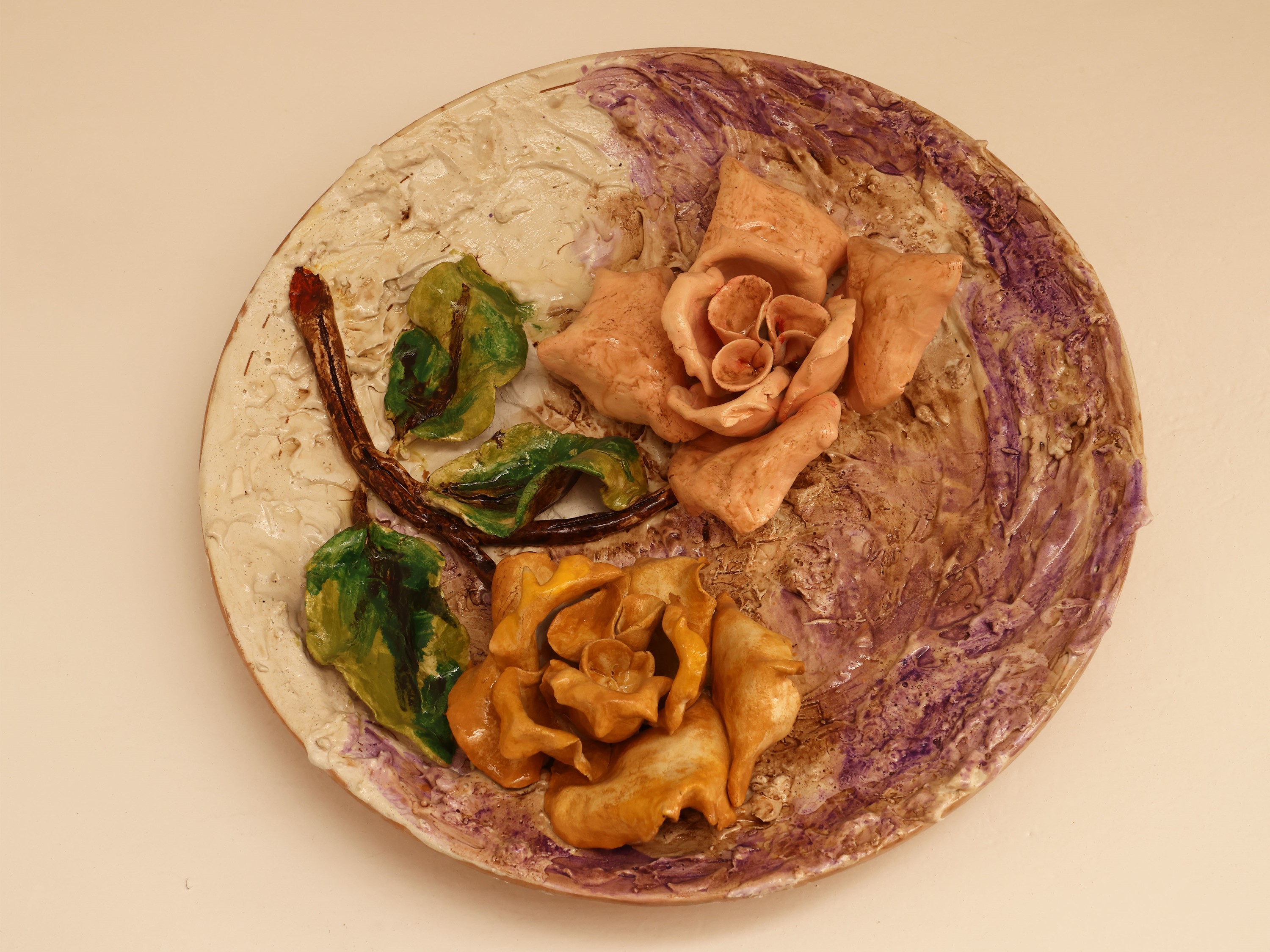 Quattro piatti da parata in ceramica policroma, decorati con motivi floreali in rilievo