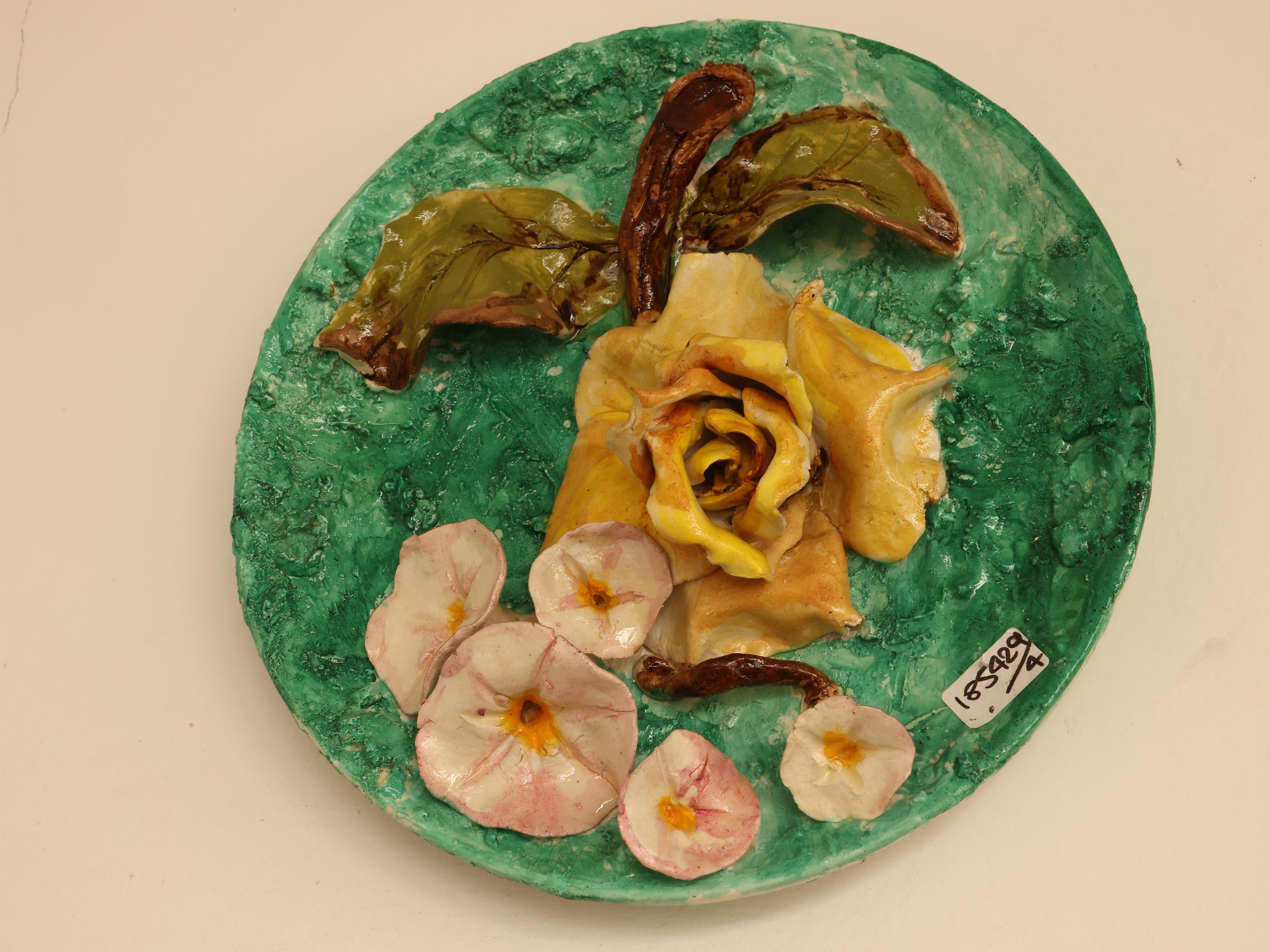 Quattro piatti da parata in ceramica policroma, decorati con motivi floreali in rilievo