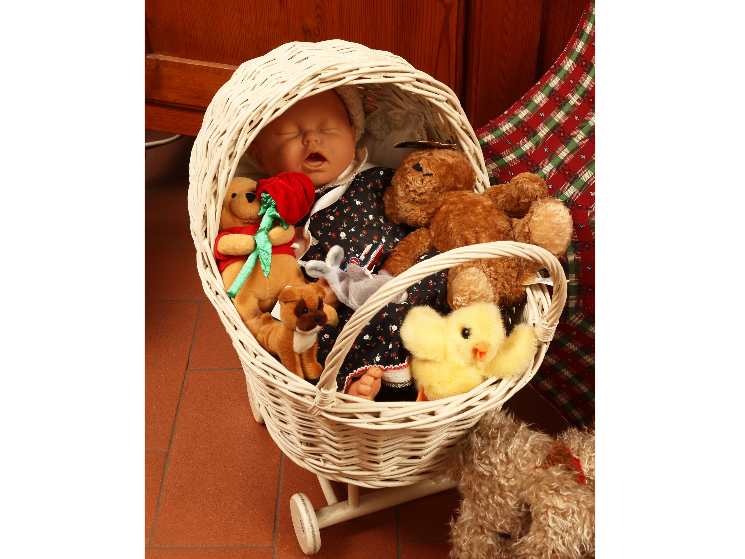 Assortimento di bambole e peluche, carrozzina in vimini, h 53 cm