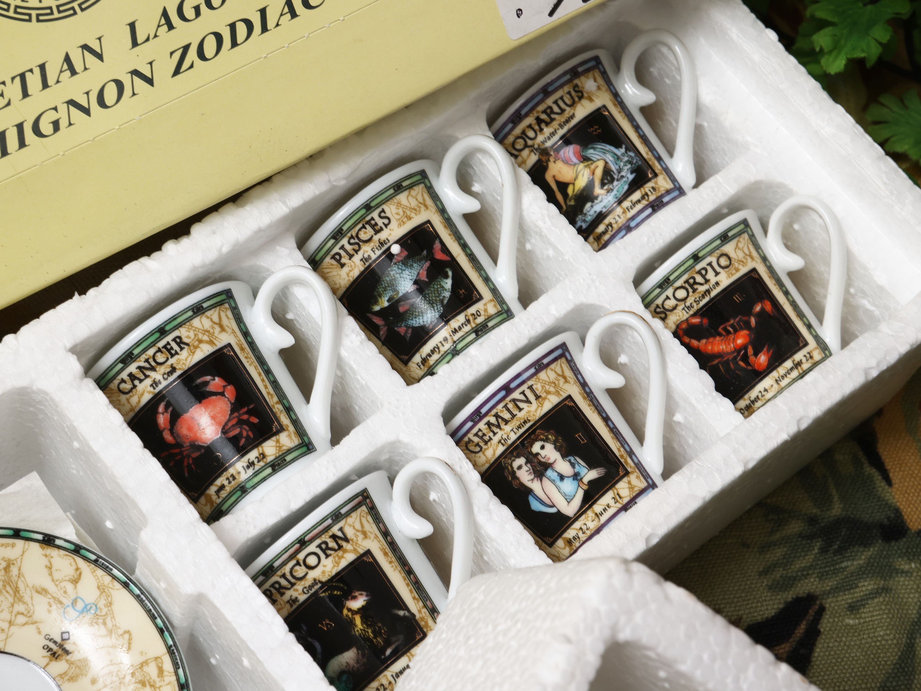 Collezione di tazzine in miniatura con decorazioni zodiacali e piattini correlati