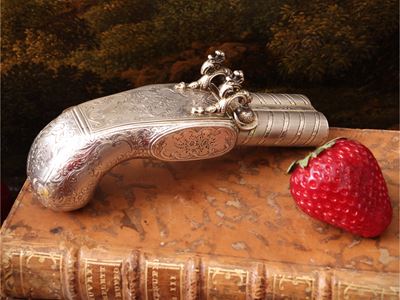 Francia (XX secolo), Scatola portatabacco a forma di pistola in argento cesellato con interno ver...