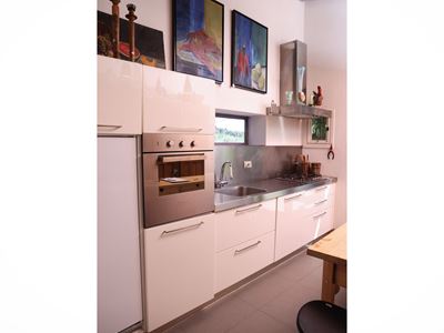 Cucina in laminato laccato bianco con piano e paraschizzi in acciaio inox