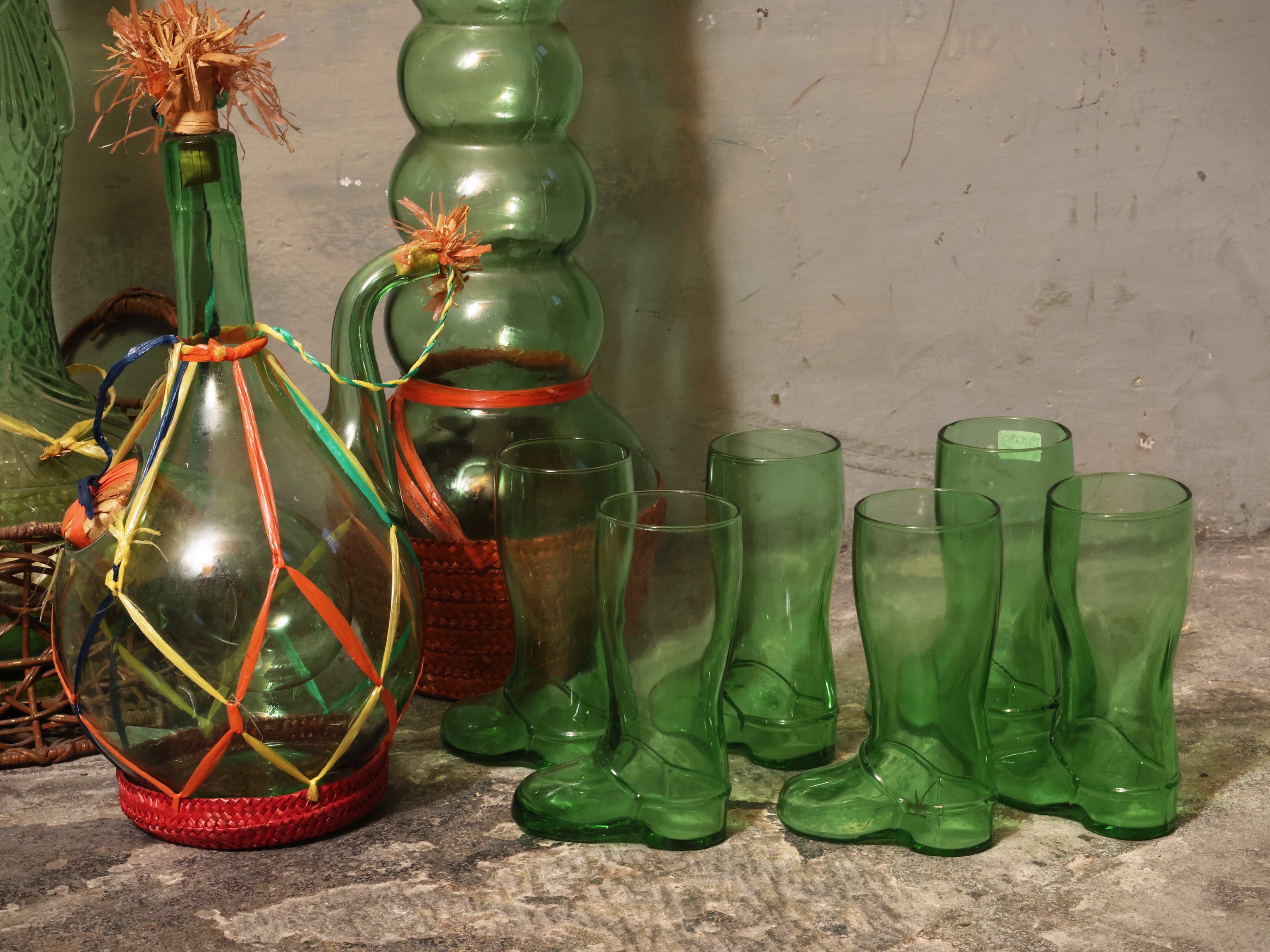Curiosità in vetro verde di Empoli, tre fiasche e serie di sei bicchieri a foggia di stivale
