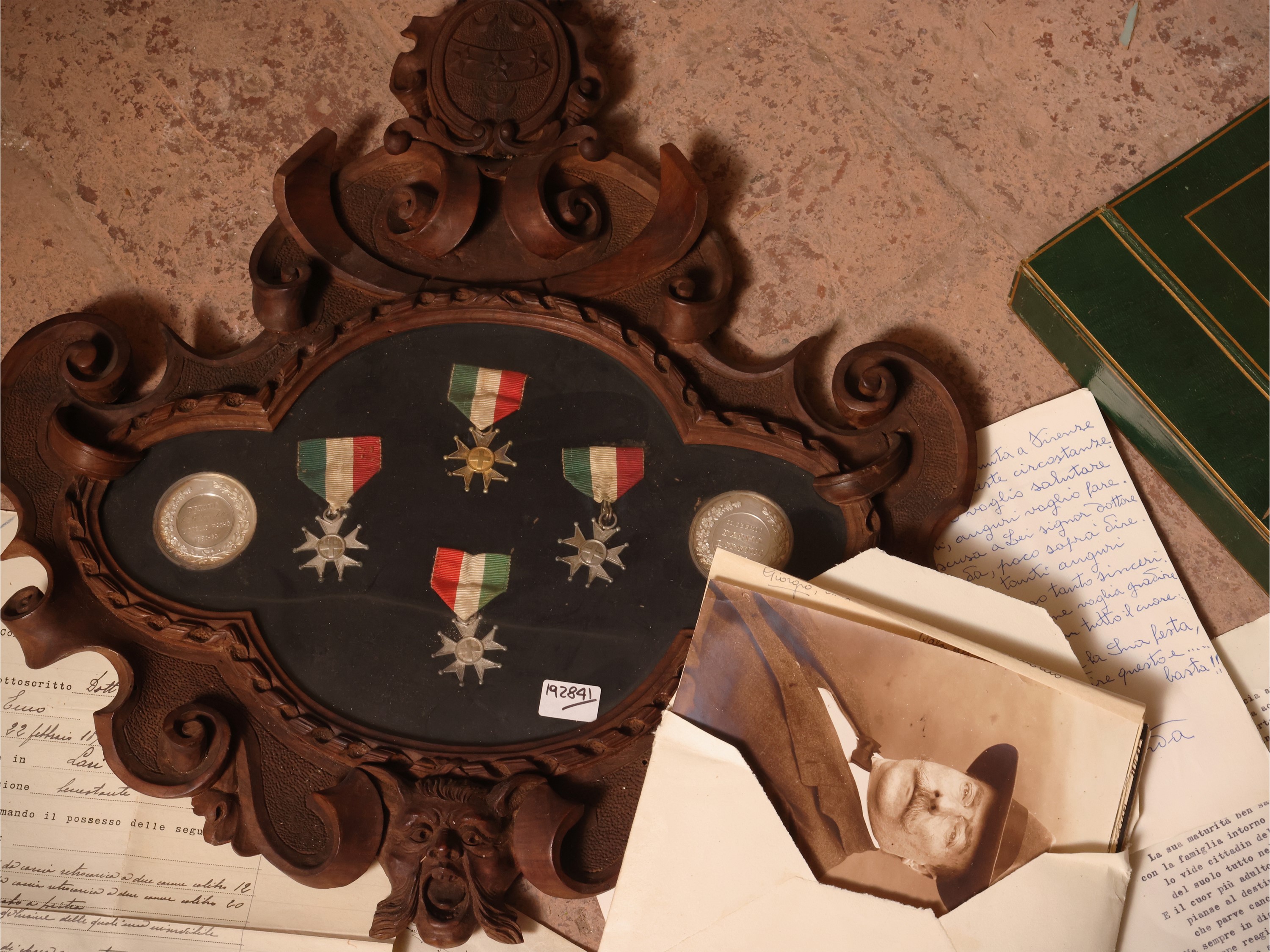 Raccolta di documenti e fotografie con cornice contenente medagliette e monete, cornice cm 43x40