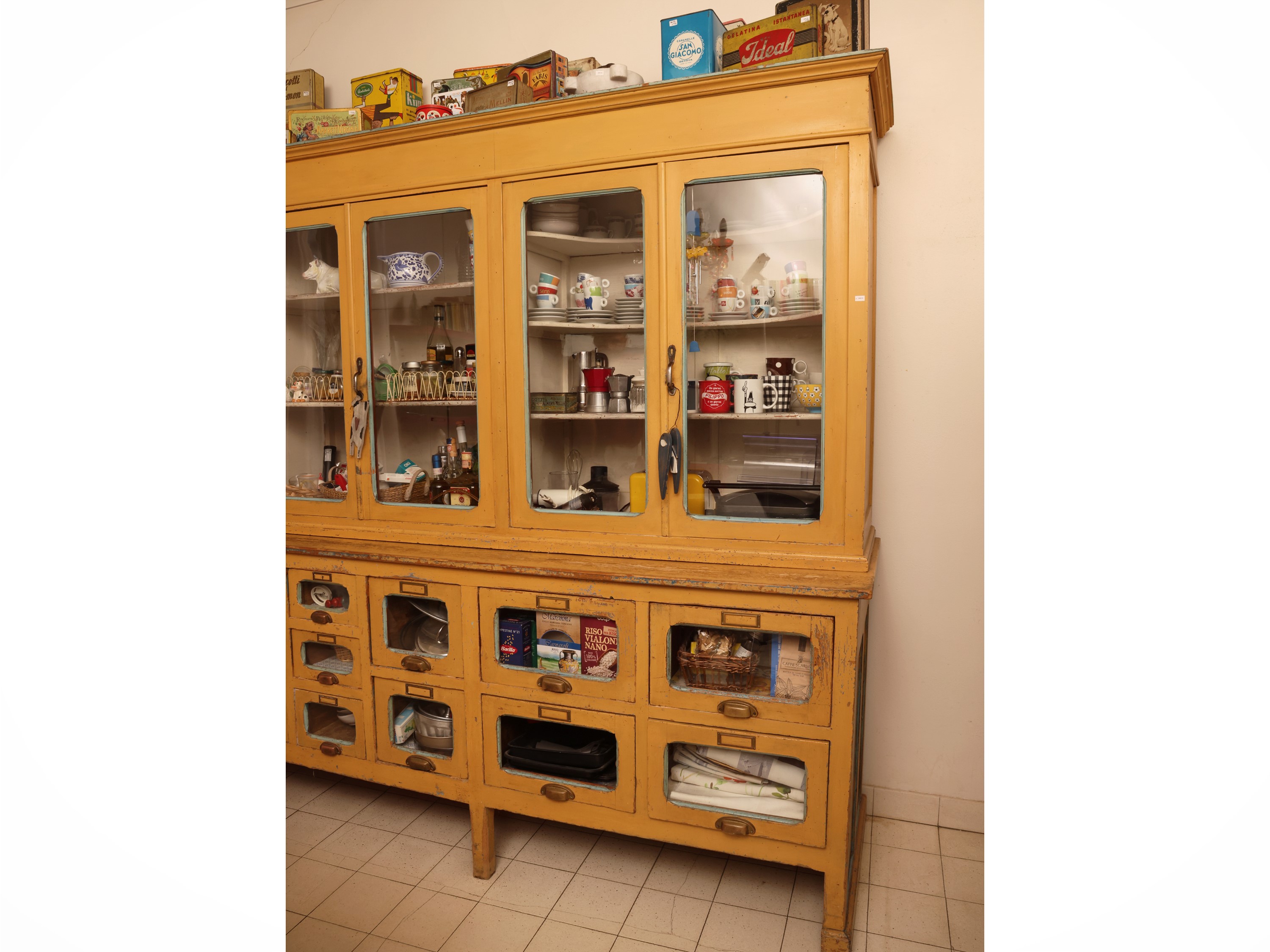 Grande mobile da farmacia in legno laccato giallo ocra, sportelli a vetro e cassetti, anni Quaran...