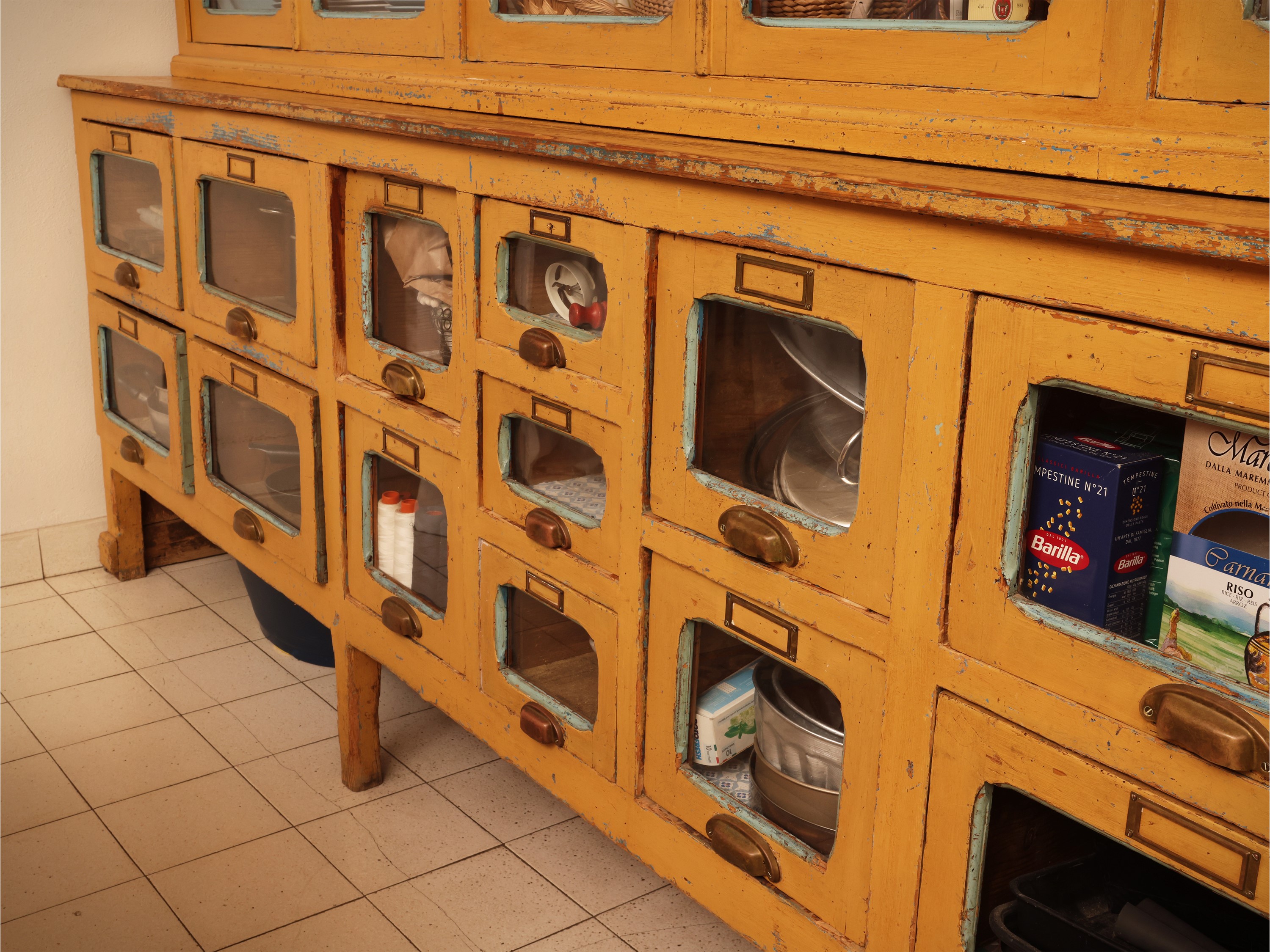 Grande mobile da farmacia in legno laccato giallo ocra, sportelli a vetro e cassetti, anni Quaran...